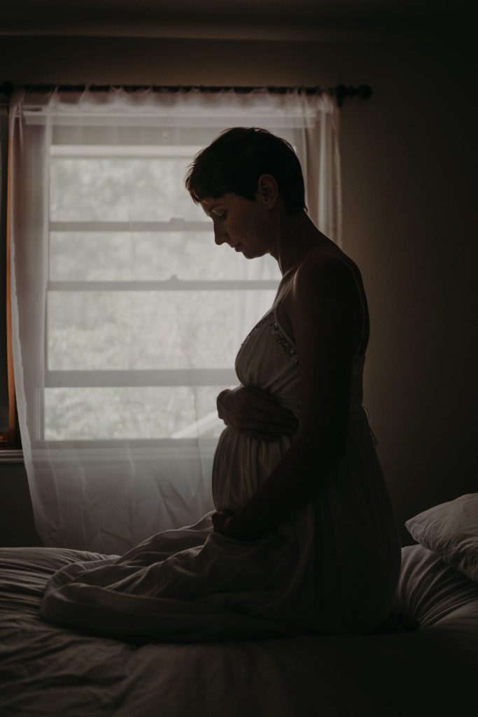 pregnant woman in white dress on bed
