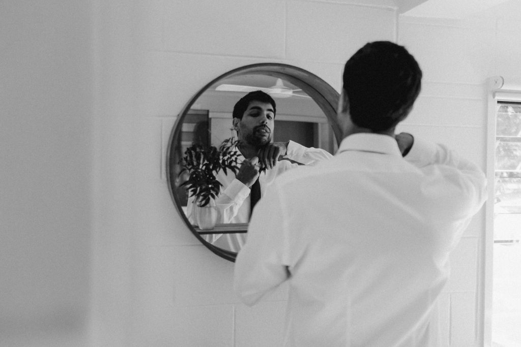groom tying tie in mirror