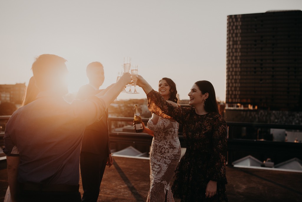 bride and groom drinking with bridal party on  rooftop for New York style elopement in Fortitude Valley Brisbane sunset