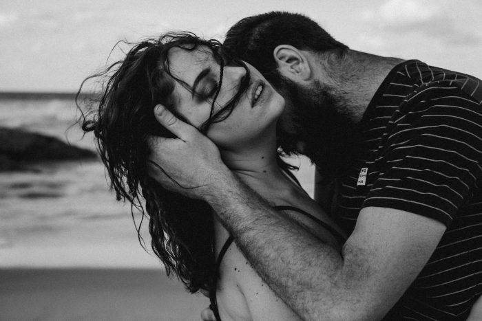 man kissing woman neck on beach sexy curls brunette