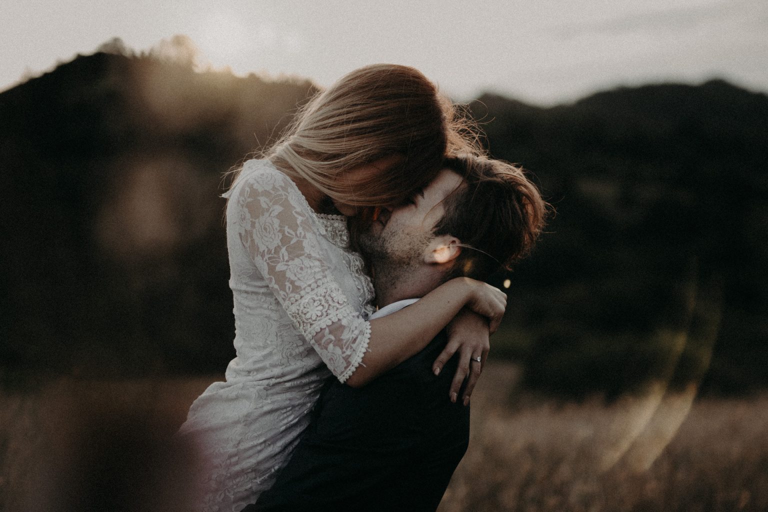 groom lifting bride kiss close face passionate sunset